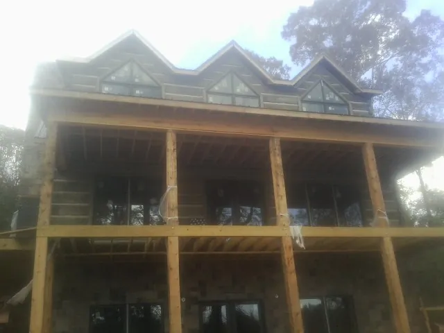 Dormers and porch framing on a large log home under construction — Roof Coating work by our crew in Polk